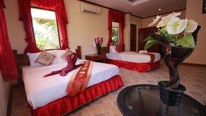 A hotel room with two beds, red curtains, a potted plant, and a round table. - Lanta Nature House (Ko Lanta)