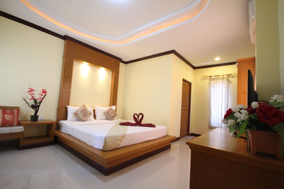 A hotel room with a bed, bedside tables, a desk, and a mirror.