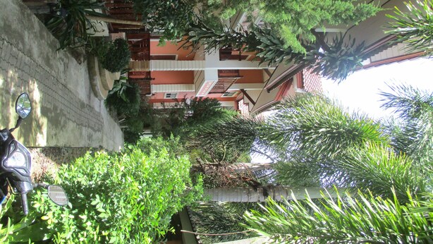 A courtyard with a staircase leading to a multi-level building, surrounded by greenery and a parked scooter. - Lanta Nature House (Ko Lanta)