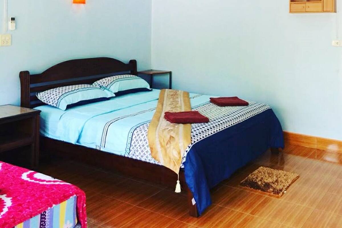 A bedroom with a bed, nightstands, a wall-mounted air conditioner, and a ceiling light fixture.