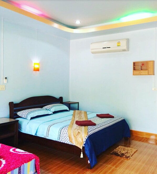 A bedroom with a bed, nightstands, a wall-mounted air conditioner, and a ceiling light fixture. - Phu Lanta Life (Ko Lanta)