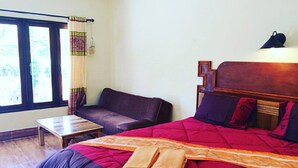 A bedroom with a large bed, a wooden headboard, a small table, a sofa, and a window with curtains. - Phu Lanta Life (Ko Lanta)