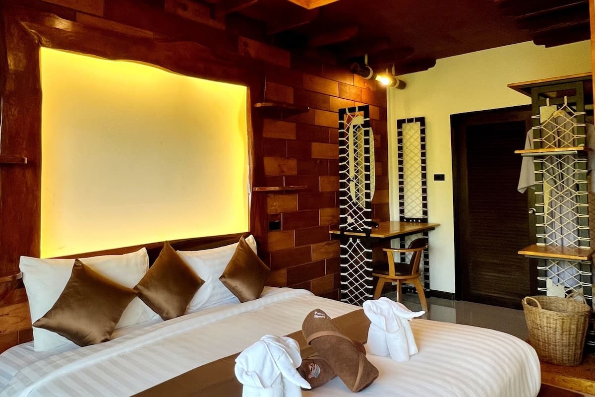 Een hotelkamer met een groot bed, houten wanden en een plafond met zichtbare balken.