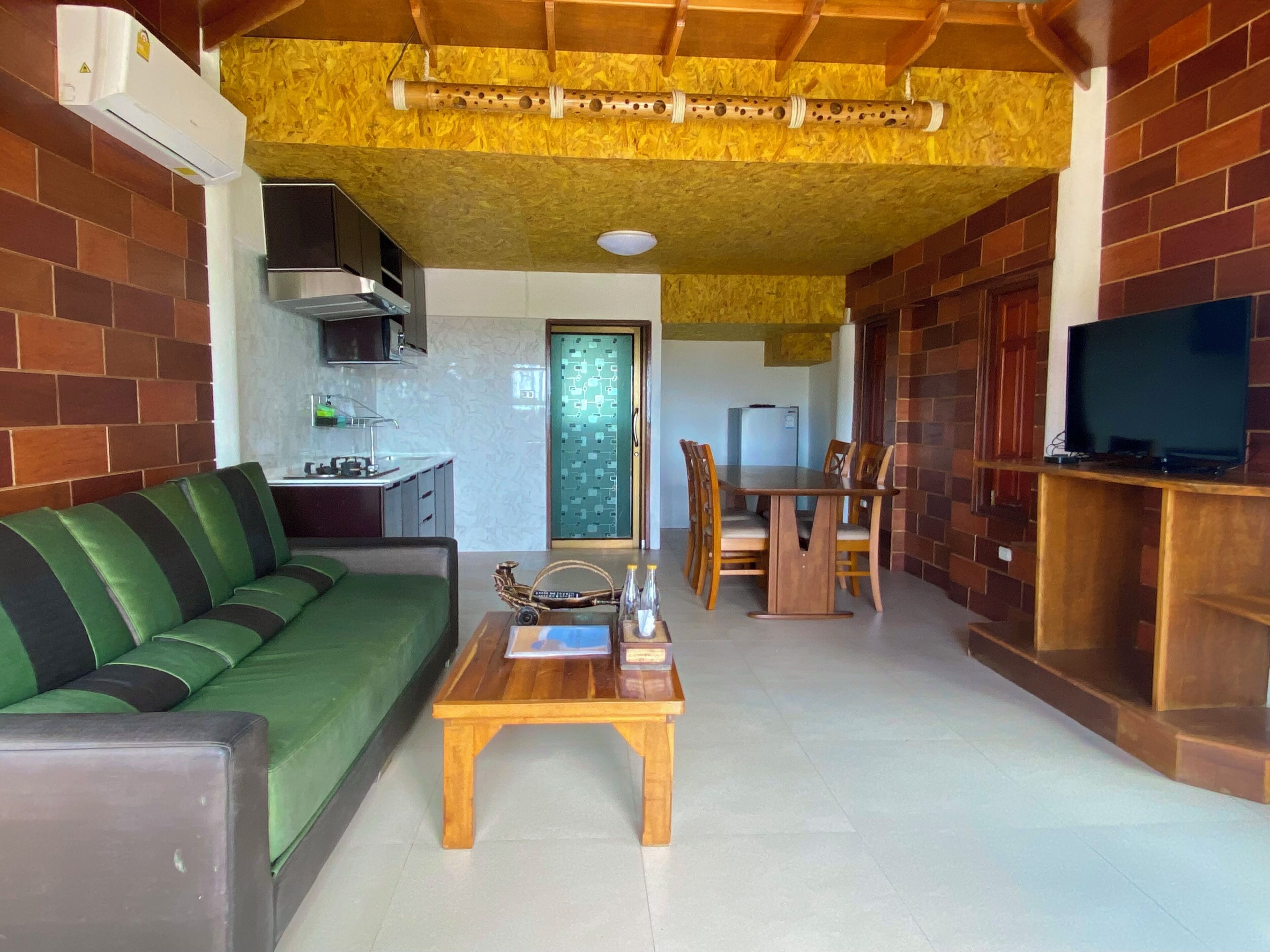 A living room with a green sofa, wooden coffee table, and a TV on a wooden stand.