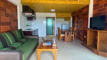 A living room with a green sofa, wooden coffee table, and a TV on a wooden stand.