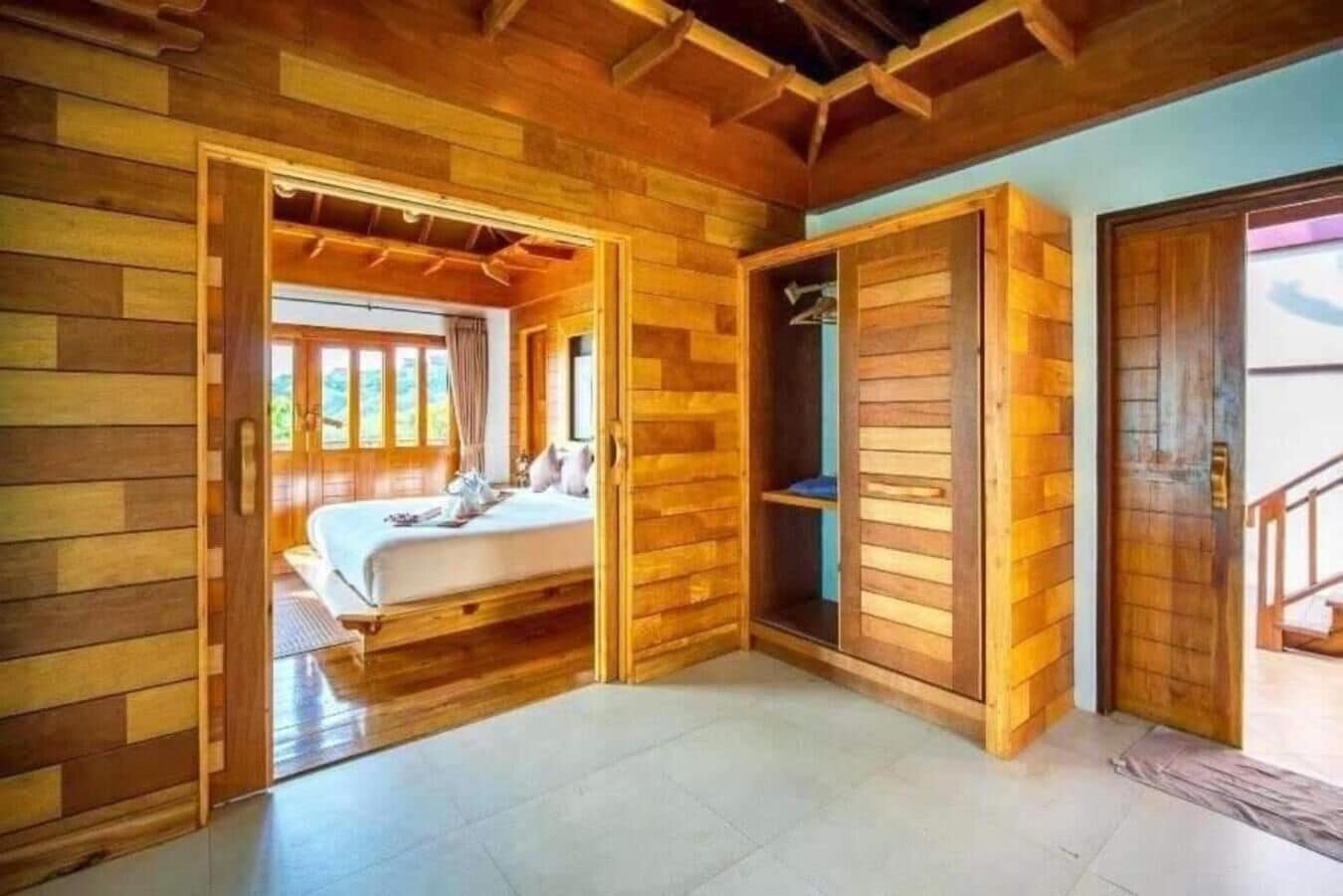 A wooden cabin room with a bed, a wardrobe, and a view of the outdoors.