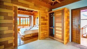 A wooden cabin room with a bed, a wardrobe, and a view of the outdoors.