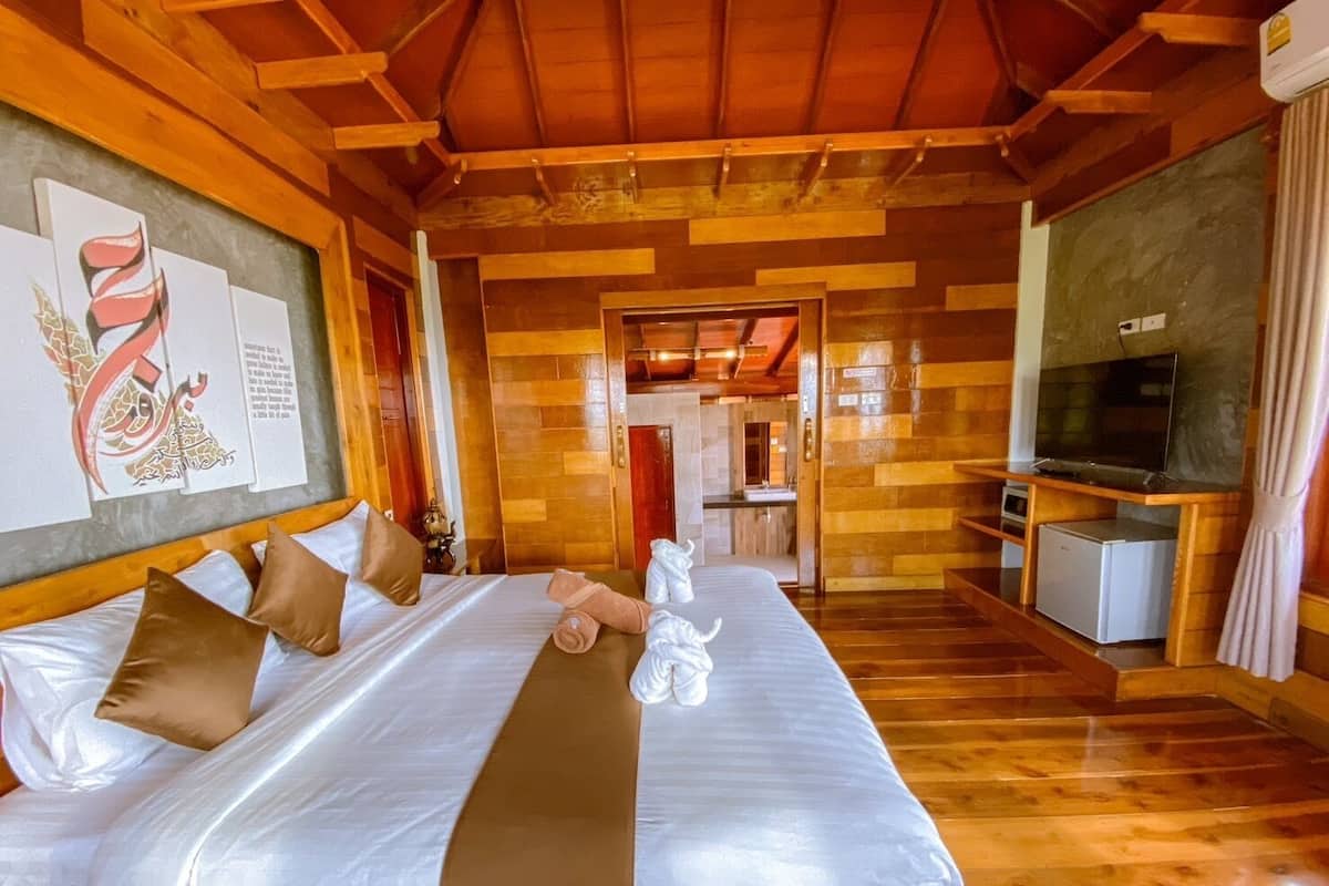 Een hotelkamer met een groot bed, een televisie en een kleine koelkast.