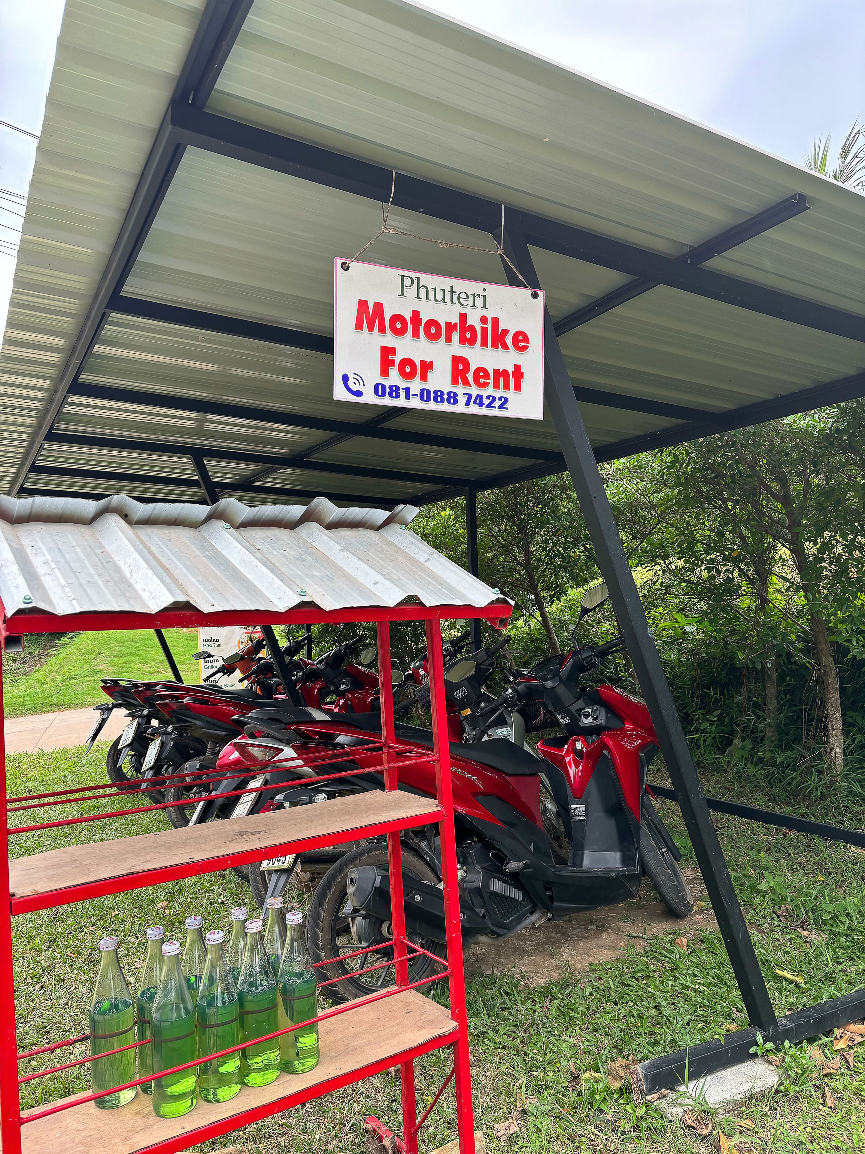 Uma área coberta para aluguel de motocicletas, com um anúncio de motos disponíveis.