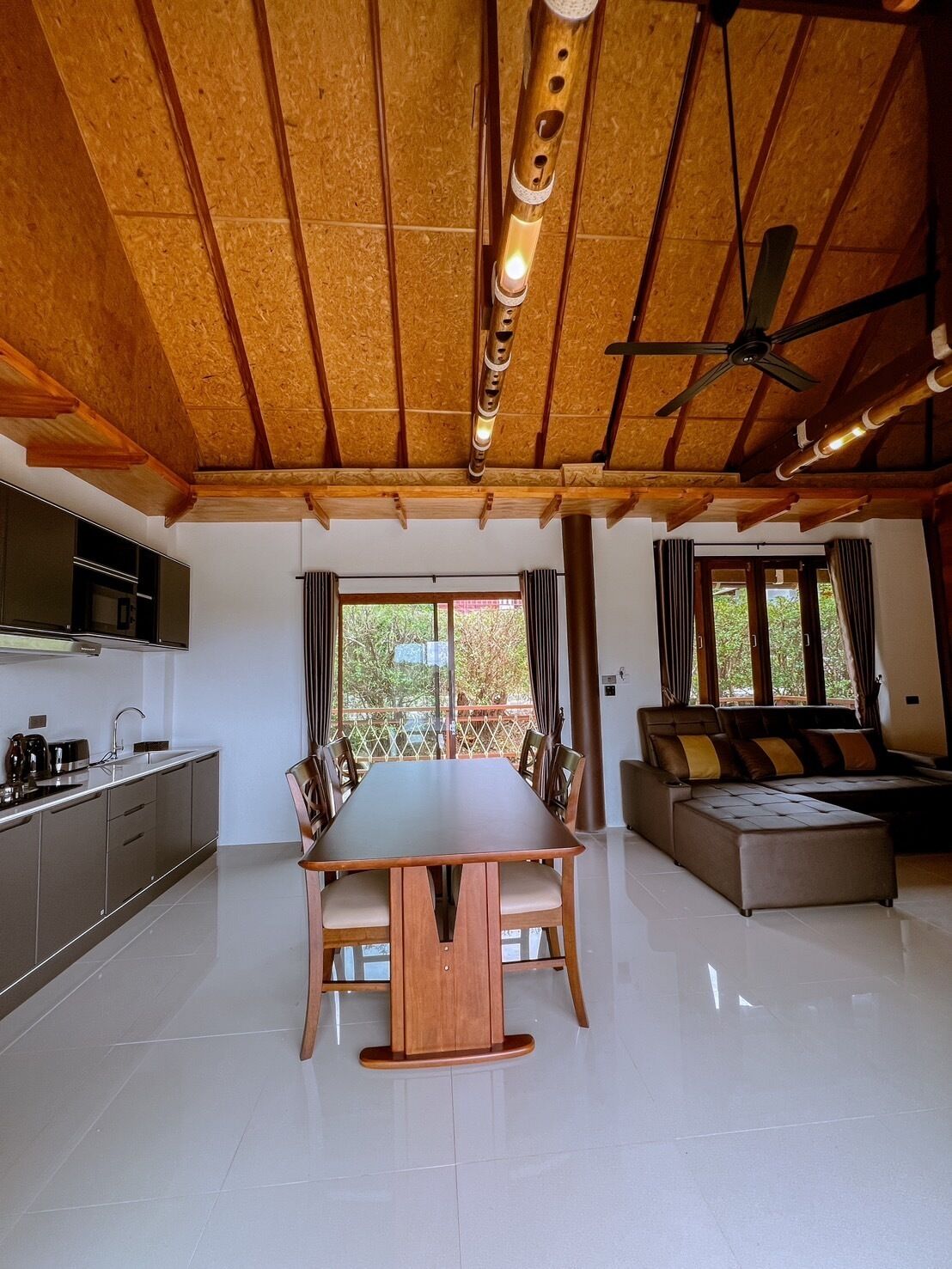 Une pièce spacieuse avec un plafond en bois, une table à manger avec des chaises, un canapé et un coin cuisine.