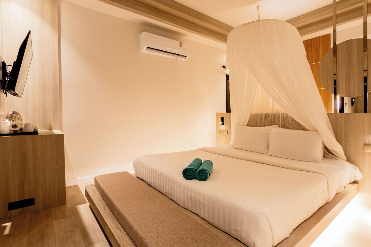 Una habitación de hotel moderna con cama, mesita de noche, unidad de aire acondicionado y televisión.