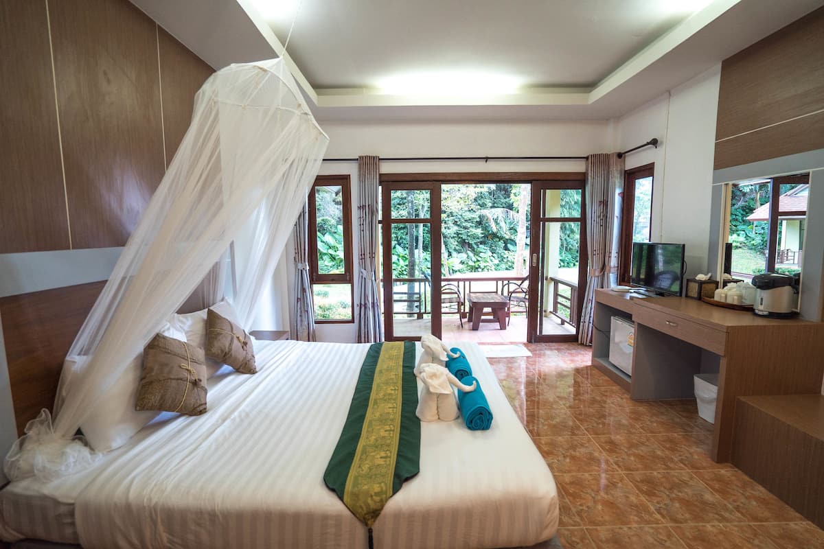 Habitación de hotel con cama, escritorio, computadora y vista al exterior.