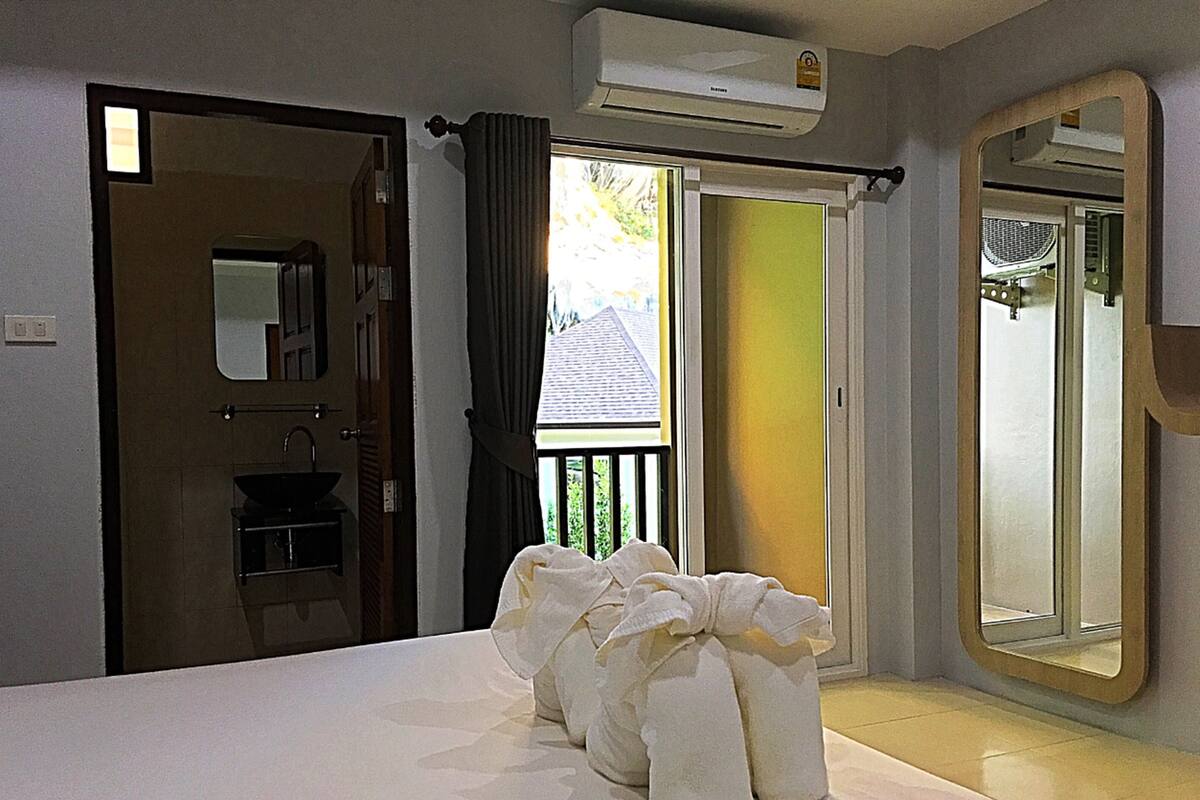 Habitación de hotel con una cama grande, un baño con lavabo y un balcón con vistas al exterior.