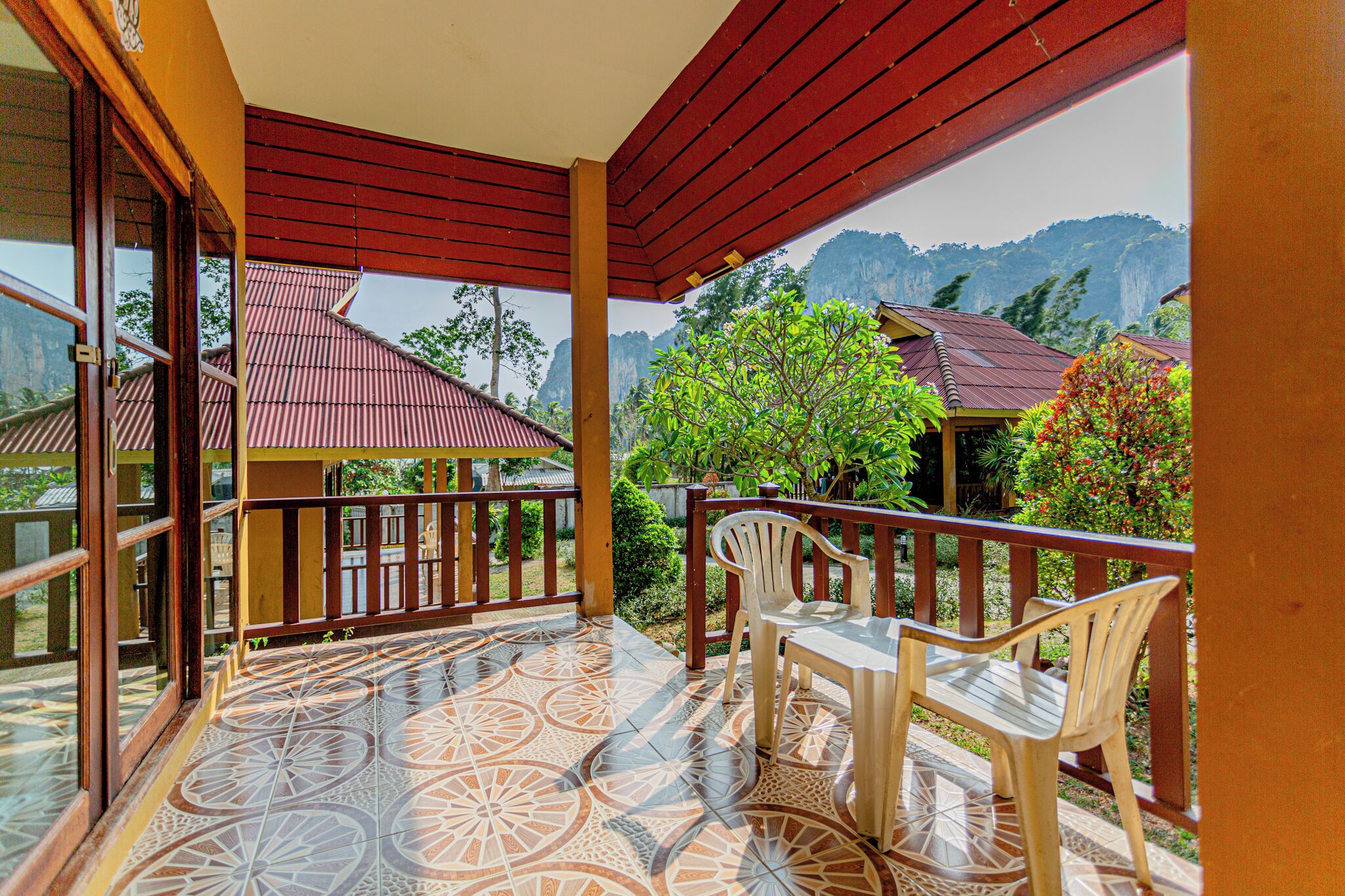 A balcony with a tiled floor, wooden railing, and a table with chairs.