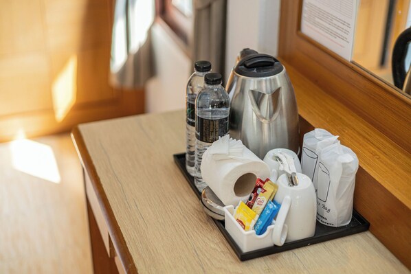 A hotel room's breakfast tray with a kettle, water bottles, a paper towel roll, a coffee mug, and a tray of condiments. - Tonsai Bay Resort (Krabi)