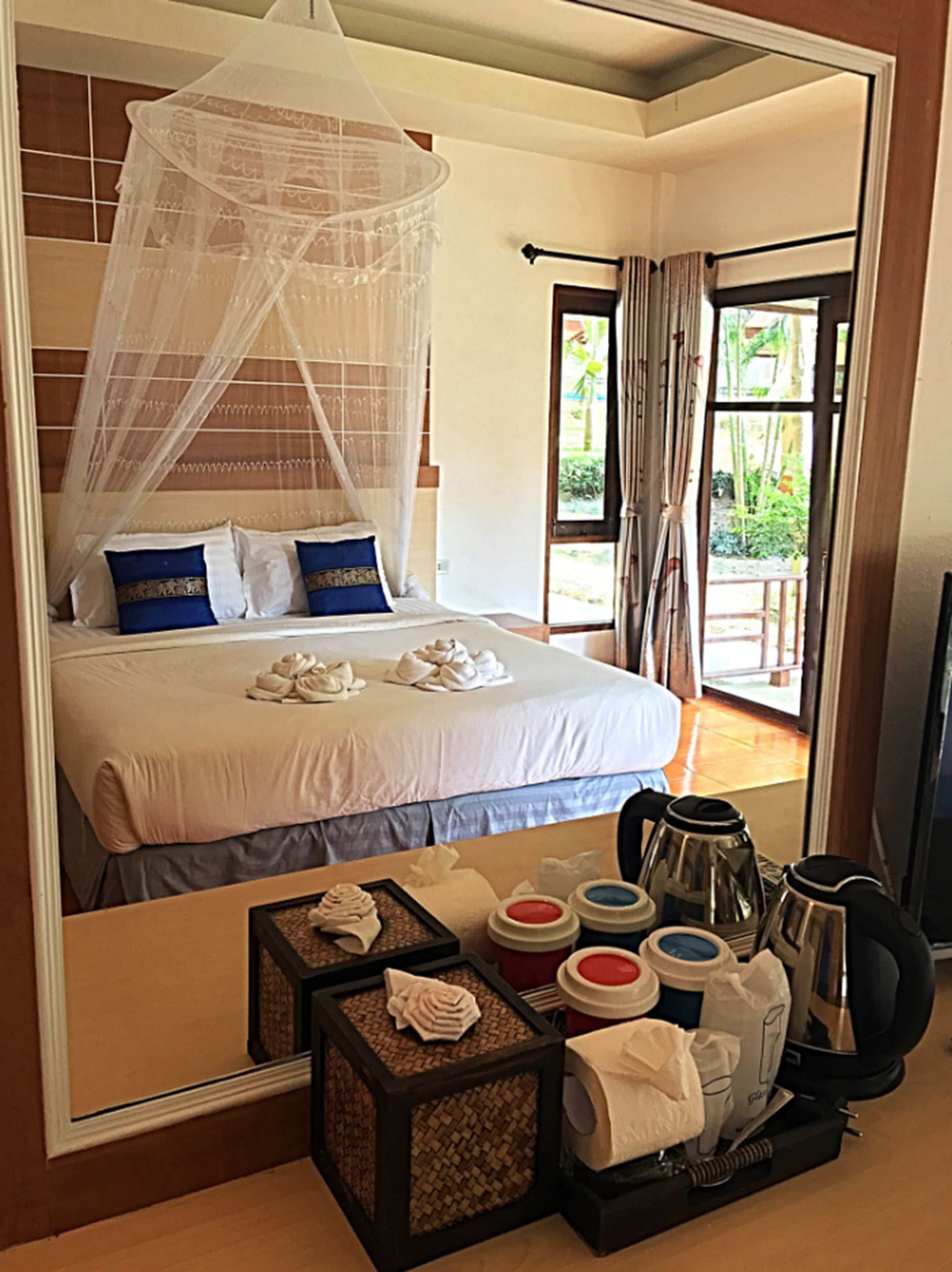 Une chambre à coucher avec un lit, un baldaquin, une table de chevet avec une bouilloire, des tasses et un plateau de serviettes.