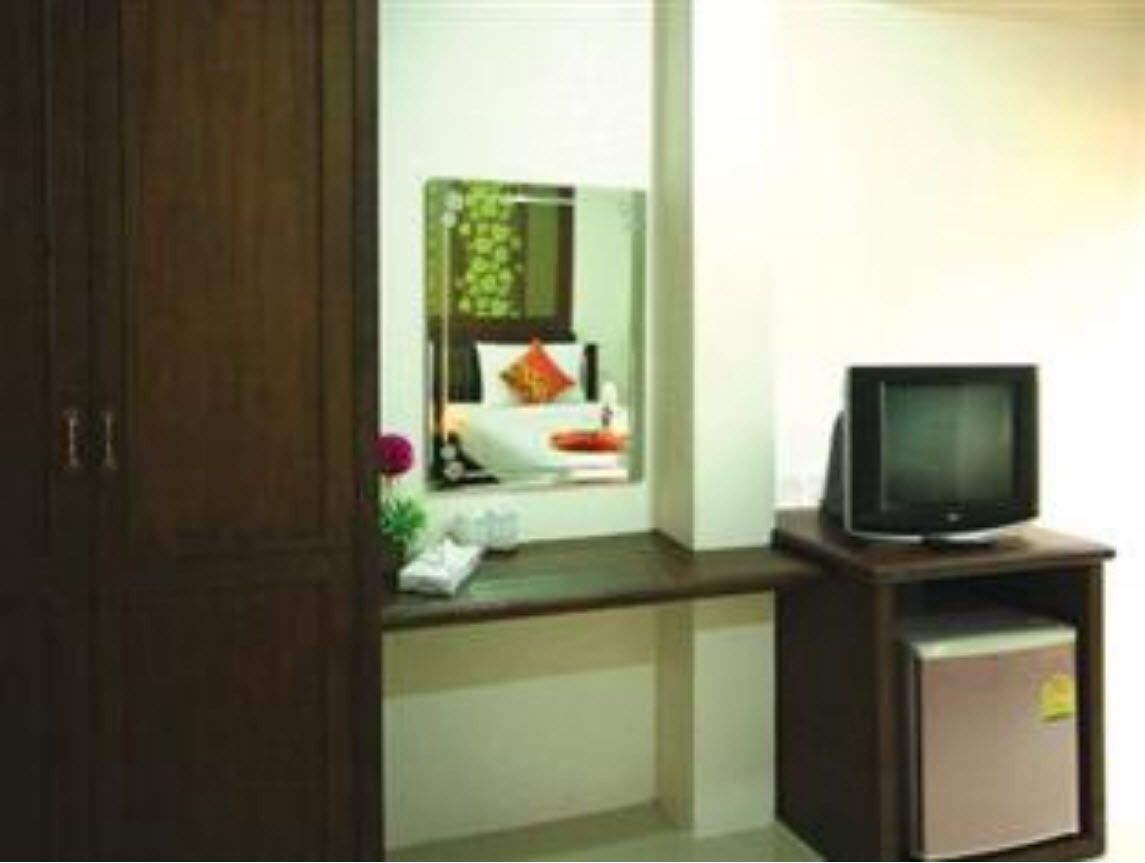 A small room with a wooden cabinet, a television on a stand, and a mirror above a counter.