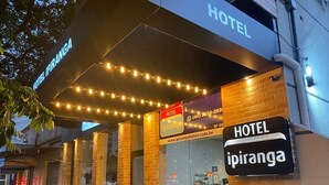 A hotel entrance with a sign reading "Hotel Ipiranga," a contact number, and a website address. - Hotel Ipiranga (Maringá)