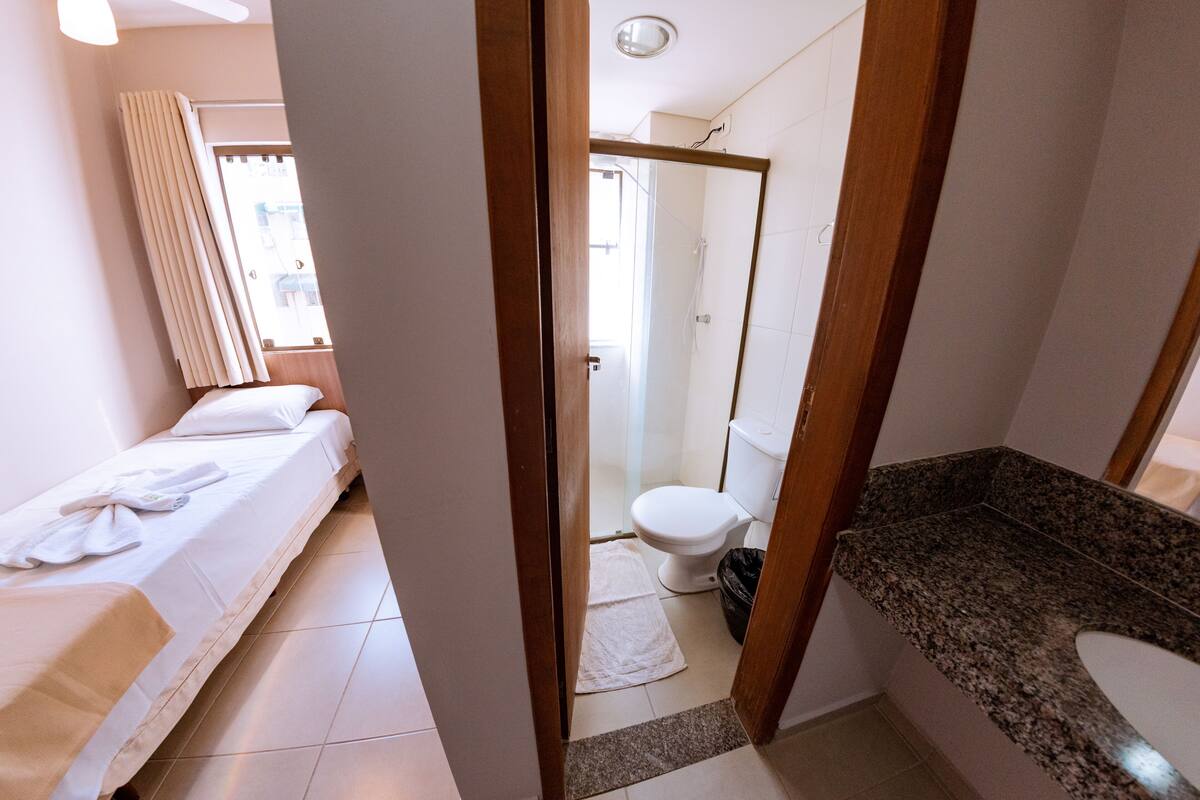 Una habitación de hotel con una cama, un baño con inodoro y ducha.