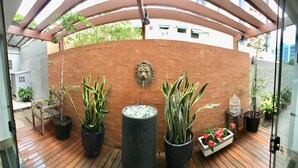 A covered patio area with potted plants, a decorative lion head, and a birdcage. - Hotel Ipiranga (Maringá)