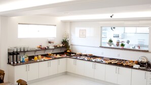 A modern kitchen with white cabinets, a granite countertop, and various breakfast items. - Roari Hotel (Cuiabá)
