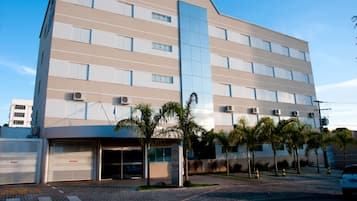 Stylish building with a flat roof and symmetrical facade, featuring evenly spaced windows and air conditioning units.