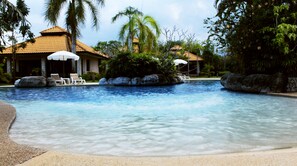 Una piscina al aire libre, sombrillas, tumbonas