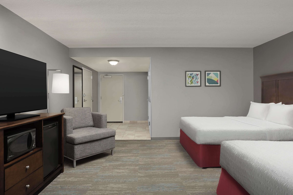 A hotel room with a TV, a sofa, a bed, and a microwave.
