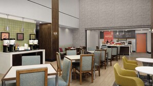 A modern hotel lobby with seating areas, a coffee station, and a waffle bar.
