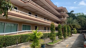 A multi-story hotel with balconies, a parking area, and landscaped greenery. - Tharapark View Hotel (Krabi)