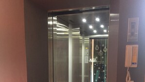 An elevator with a glass door, a wall-mounted phone, and a decorative item hanging from the ceiling. - Tharapark View Hotel (Krabi)