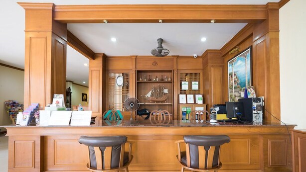 A wooden reception desk with two leather chairs, a ship model, and various certificates and awards on display. - Pranang Flora House (Krabi)