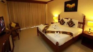 A hotel room with a large bed, a desk, and a chair. - Pranang Flora House (Krabi)