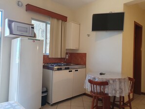 Une cuisine compacte équipée d’un four à micro-ondes, d’une cuisinière et d’une petite table à manger avec des chaises.