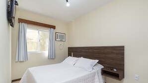 Ein Schlafzimmer mit einem Bett, einem Vorhangfenster, einer Wandklimaanlage und einem Holzkopfschild.