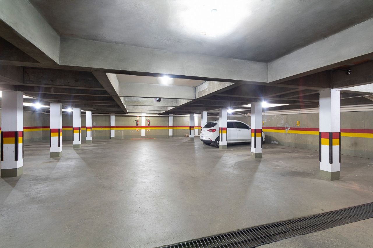 A multi-level parking garage with concrete pillars and a white car parked in one of the bays.