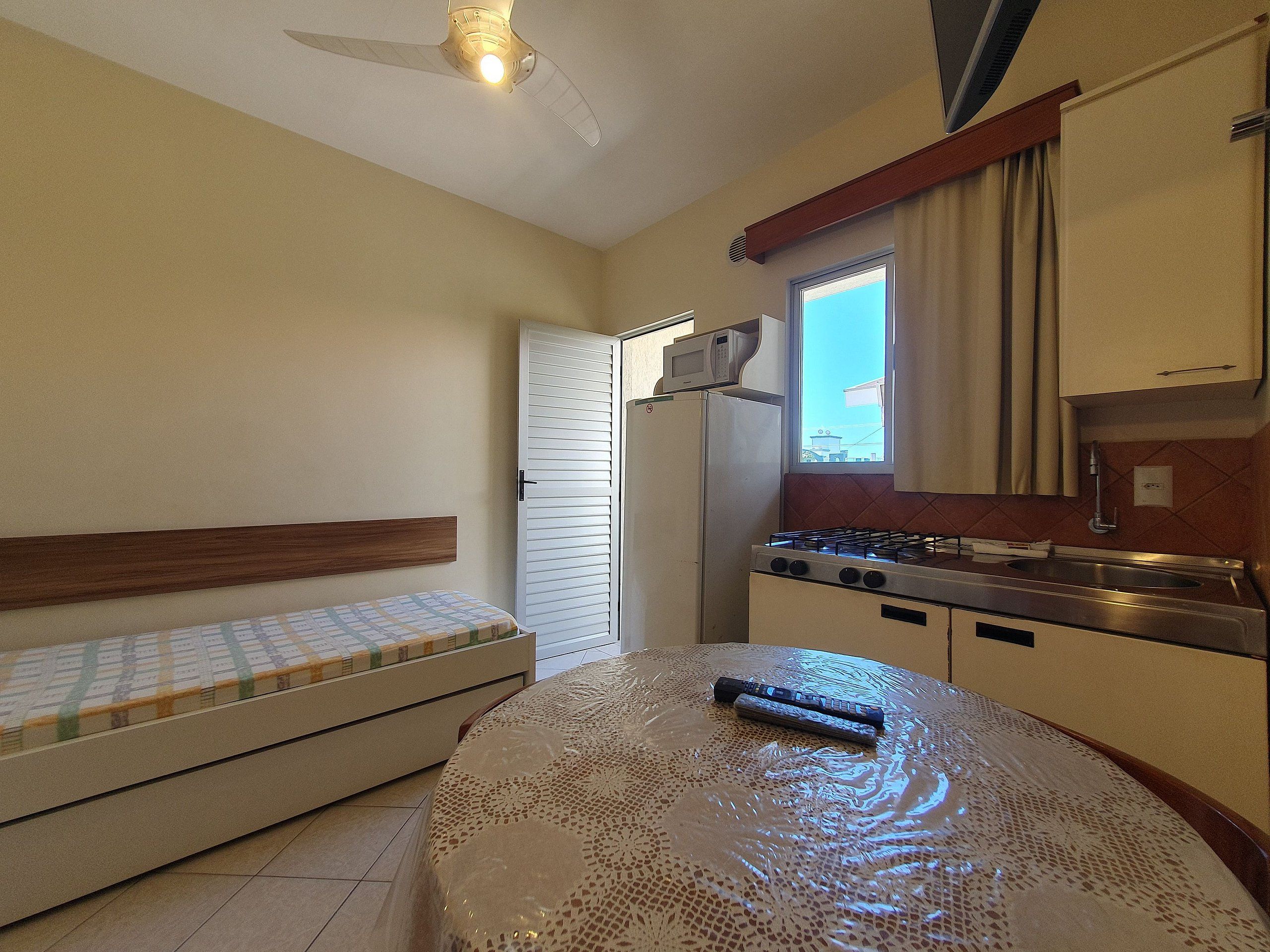 A compact kitchen with a refrigerator, stove, and a microwave on the countertop.