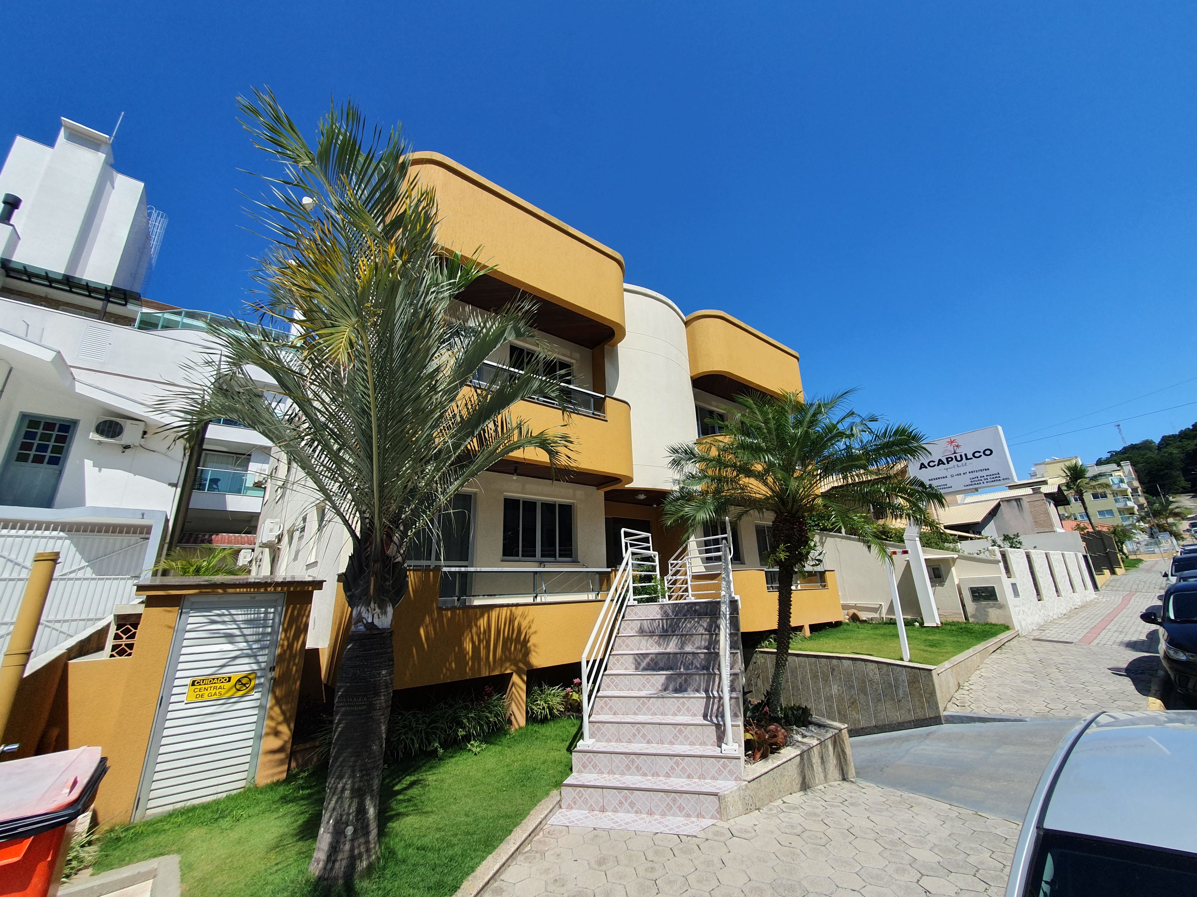 A multi-story residential building with a yellow facade, a visible staircase, and a signboard.
