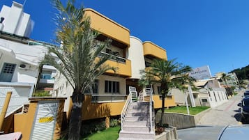 A multi-story residential building with a yellow facade, a visible staircase, and a signboard.