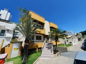 Un immeuble résidentiel à plusieurs étages, doté d’une façade jaune, d’un escalier apparent et d’une enseigne.