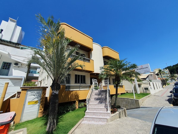 Un edificio residencial de varios pisos con fachada amarilla, una escalera visible y un cartel.