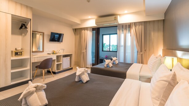 A hotel room with two beds, a desk, a chair, a TV, and an air conditioning unit. - Lada Krabi Residence (Krabi)