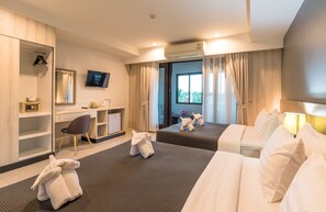 Habitación de hotel con dos camas, un escritorio, una silla, un televisor y un equipo de aire acondicionado.