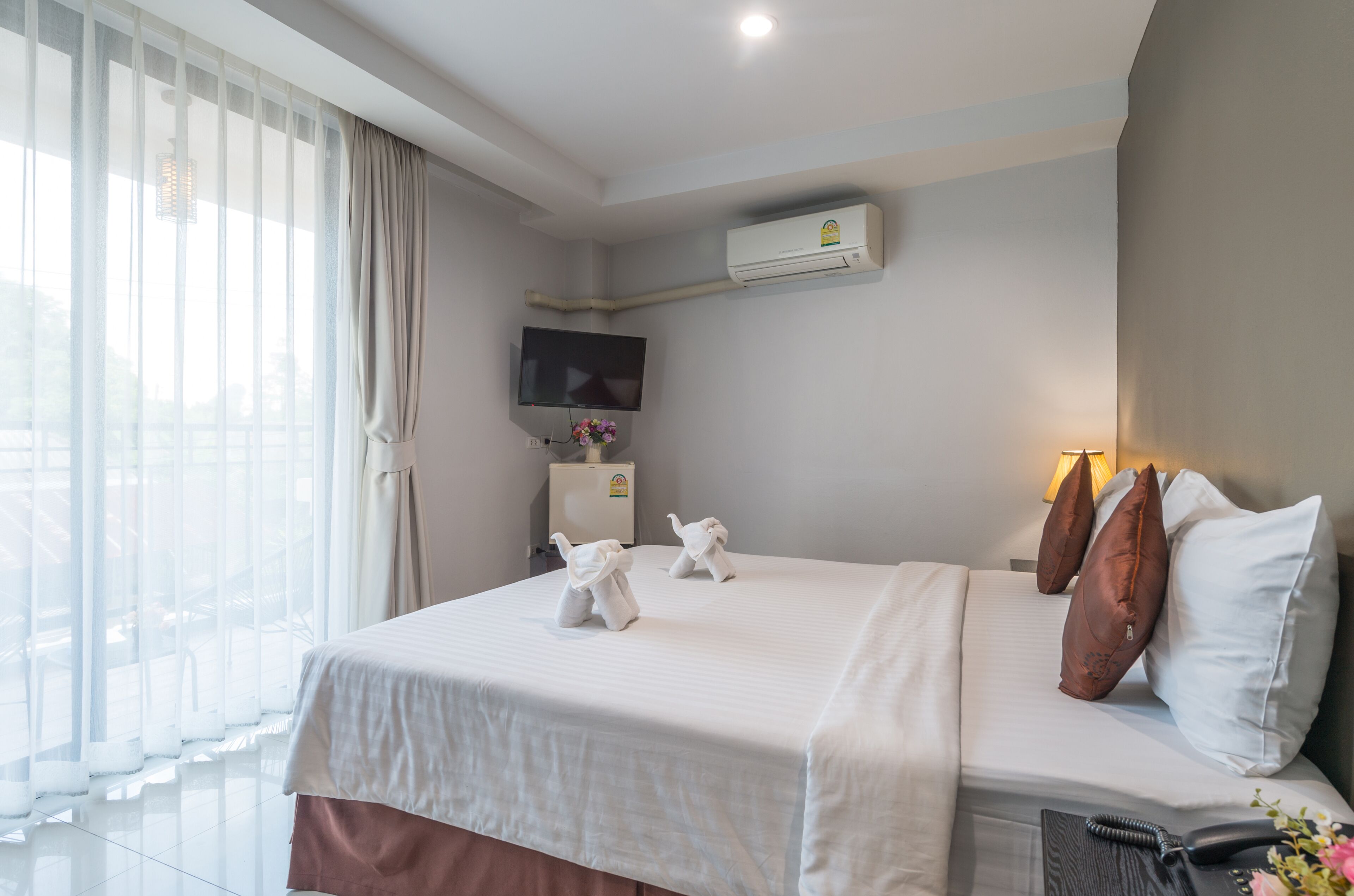 Une chambre d’hôtel équipée d’un lit, de la climatisation, d’une télévision et d’une fenêtre avec des rideaux.