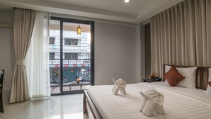 A hotel room with a large bed, a nightstand, a lamp, and a view of a building through a sliding door. - Lada Krabi Residence (Krabi)