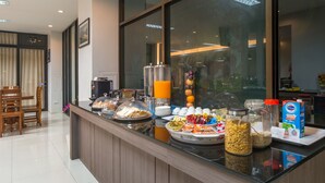 A breakfast buffet with various food items and beverages, a wooden dining area, and a large window with a view. - Lada Krabi Residence (Krabi)