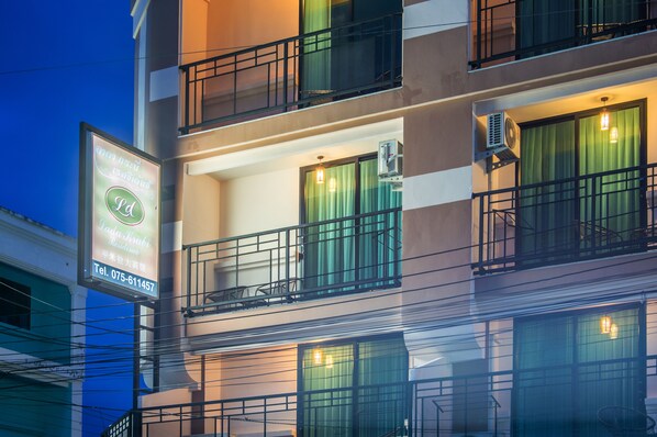 Un hotel de varios pisos con balcones, unidades de aire acondicionado y un cartel.