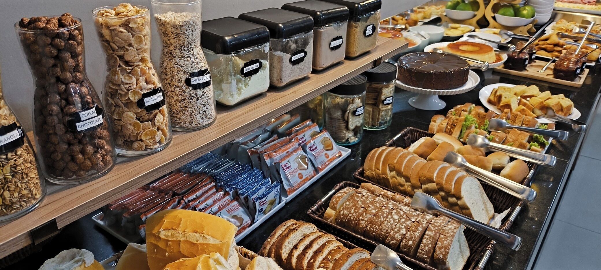 A buffet with various food items including cereals, bread, and pastries.
