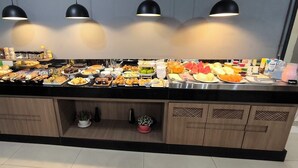 Un buffet con diversi cibi e bevande, un lavandino e mobili in legno.