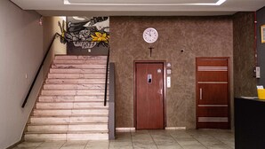 Una scala che conduce a un ascensore, una sveglia appesa al muro e una porta con un cartello.